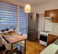 A kitchen with a stove, refrigerator, and a wooden decor floor in a 4-room apartment.