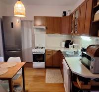 A kitchen with a wooden decor floor, dining table, appliances, bright interior in a 4-room apartment.