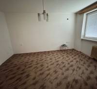 A room in a one-room apartment with a wooden decor floor and simple lighting.