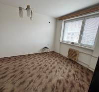 A room in a one-bedroom apartment with a window, white walls, and a floor with a wood decor.