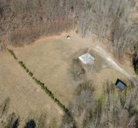 Aerial view of Recreational plots in Kľak, surrounded by forest and divided by a road.