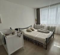 Bedroom in a 2-room apartment with a crib, bed, and dresser, floor with wooden decor.