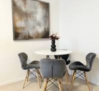 Dining area with four gray chairs and a table in a 2-room apartment.