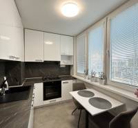 A kitchen in a 2-room apartment with white furniture and a dark countertop.