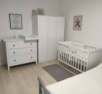 Children's room with white furniture and a wooden decor floor in a 2-room apartment.