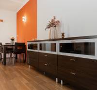 Dining room in a 2-room apartment with an orange wall and a wood-patterned floor.