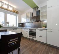 Kitchen in a 2-room apartment with white cabinets and a wood-patterned floor.