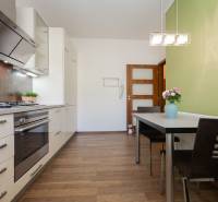 A kitchen in a 2-room apartment with white cabinets, a green wall, and a floor with a wood decor.