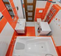 The bathroom of a two-room apartment with striking orange and white tiles and sanitary equipment.