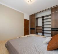 Bedroom in a 2-room apartment with a bed and a large wardrobe, floor with wood decor.