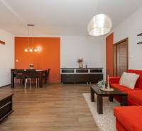 Living room in a 2-room apartment, orange wall, red sofa, floor with wooden decor.