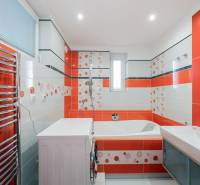 A colorful bathroom with a bathtub, sink, and washing machine in a 2-room apartment.