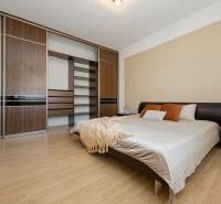 Bedroom in a two-room apartment with wood-patterned flooring and a large wardrobe.