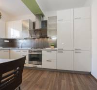 Kitchen in a 2-room apartment with white cabinets and a wood-patterned floor.