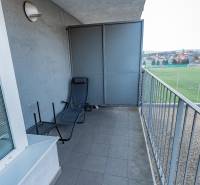 A balcony of a 2-room apartment with a view of the football field and a lounger.