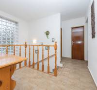 A family house with a wooden table, railing, and a large glass block window.
