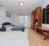 Bedroom in a family house with a wood-decor floor, contains a double bed and wooden furniture.