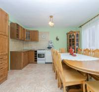 A kitchen in a family house with wooden furniture and a dining table.