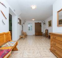 Family house with a vestibule, wooden furniture, hunting decorations on the walls, tiled floor.