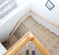 A staircase in the interior of a family house with light tiles and a wooden railing.
