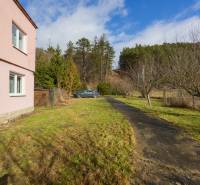 A family house in Tŕstie with a road and a car in the garden on a sunny plot.