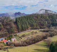 A family house in Tŕstie surrounded by nature and forests, with hills in the background.