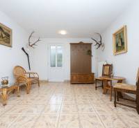 Interior of a family house with a rattan sofa, chairs, decorative antlers, and paintings.