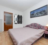 A bedroom with a wood-patterned floor in a family house, with a decorated picture on the wall.