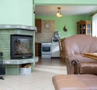Interior of a family house with a fireplace, a sofa set, and a kitchenette in natural shades.