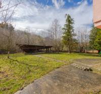 The garden of a family house in Tŕstie with a lawn, trees, and a wooden gazebo.