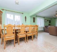Dining room with wooden furniture, light walls, and a wooden decor floor in a family house.