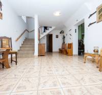 The interior of a family house with ceramic flooring, a staircase, wooden furniture, and historical decorations.