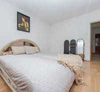Bedroom in a family house with a wood-decor floor, a comfortable bed, and a picture on the wall.