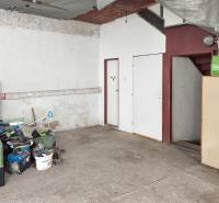 A garage in a family house, stored tools, concrete floor, stairs, and white furniture.