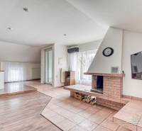 Living room with a fireplace in a family house, floor with wooden decor, spacious windows.