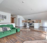 Interior of a family house with a sofa, kitchenette, and wooden decor flooring.