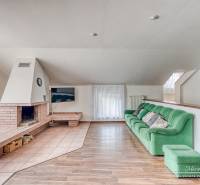 Living room in a family house with a fireplace, green sofa, and wooden decor flooring.