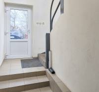 The entrance hallway of a family house with a tiled floor and white walls.
