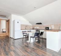 A kitchen with a dining table and appliances in a family house, with a wooden decor floor.