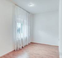 A bright room with a wood-patterned floor and curtains in a family house.