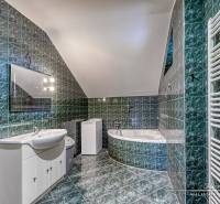 A bathroom with green tiles and white sanitary ware in a family house.