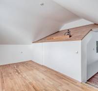 Attic room with white walls and a wooden decor floor in a family house.