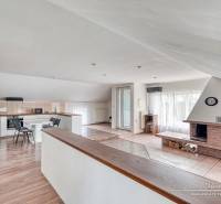 Living room with a fireplace and kitchen area, wooden decor flooring, bright room.