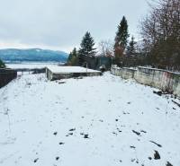 Snow-covered recreational plots in Považská Bystrica with a view of the surrounding mountains.