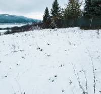 A snow-covered area in the Recreational Grounds near Považská Bystrica, bordered by a fence and trees.