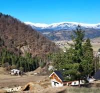 Snow-covered mountains and cottages surrounded by forests and farmland near Hronec.