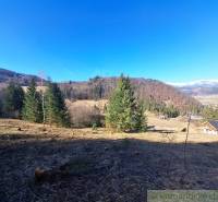 Agricultural and forest land near Hronec, surrounded by trees and hills on the horizon.
