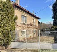 A family house in Bretka with a living hedge and a metal gate on a fenced plot.