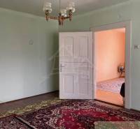 A room in a family house with a carpet, white doors, and a chandelier.