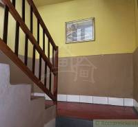 A staircase with a wooden railing in a family house with yellow walls and a painting.